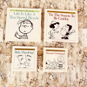 May include: Four vintage Peanuts comic books. The titles include "Life Is Like A Ten-Speed Bicycle", "'Tis The Season To Be Crabby", "Bah, Humbug!", and "Season's Greetings!". Each book features black and white illustrations of the Peanuts characters.