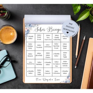 May include: A printable sobriety bingo card with a floral design. The card has a grid of 25 squares with different sobriety milestones, such as "Sober Month", "Sober Work Event", "Sober New Year's Eve", "Sober Family Gathering", and "Sober 7 Months". The card also includes the text "Sober Bingo" and "One Day at a Time".