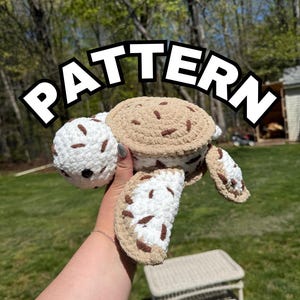 May include: A plush crochet turtle toy featuring a white and tan speckled shell and limbs with dark brown accents. The word PATTERN is displayed in large white letters with a black outline across the top portion of the image.