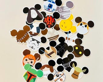 May include: A collection of colorful Star Wars-themed stickers in the shape of Mickey Mouse ears. The stickers feature various characters and elements from the Star Wars franchise, including Darth Vader, R2-D2, and Chewbacca.