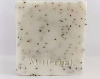 May include: A rectangular bar of soap with a light cream color and speckled with small, dark brown seeds. The words "Al Herbal" are embossed on the front of the soap. The soap is set against a plain white background.