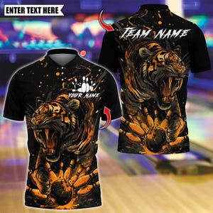 Puede incluir: Polo negro con un gráfico de tigre rugiente con acentos naranjas y marrones. El diseño incluye bolos y una bola. El texto en la camisa dice "YOUR NAME" y "ENTER TEXT HERE". La parte posterior de la camisa dice "TEAM NAME".