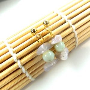 May include: A pair of gold-tone stud earrings featuring dangling charms composed of pale lavender irregular stone chips and smooth, round, light green beads. The earrings are secured with gold-tone ball studs and connected by small gold-tone jump rings.