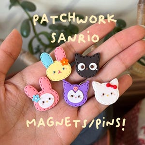 Peut inclure: Un ensemble d'aimants/épingles Sanrio patchwork colorés. L'ensemble comprend des personnages tels qu'un lapin jaune aux oreilles bleues, un lapin rose, un chat noir, un personnage violet et un chat blanc avec un nœud rouge. Texte : "PATCHWORK SANRIO MAGNETS/PINS!"