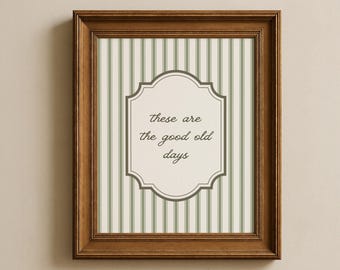 May include: A framed print with the text "these are the good old days." The print has a striped background in shades of green and white. The frame is made of dark brown wood.