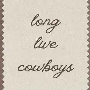 May include: A beige fabric with brown vertical stripes and a decorative edge. The words "long live cowboys" are written in a cursive font in the center of the fabric.