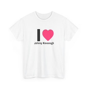 May include: A white short-sleeved t-shirt featuring a graphic on the chest. The graphic consists of a black vertical rectangle, a bright pink heart symbol, and the black text Johnny Kavanagh printed directly underneath the heart and rectangle.