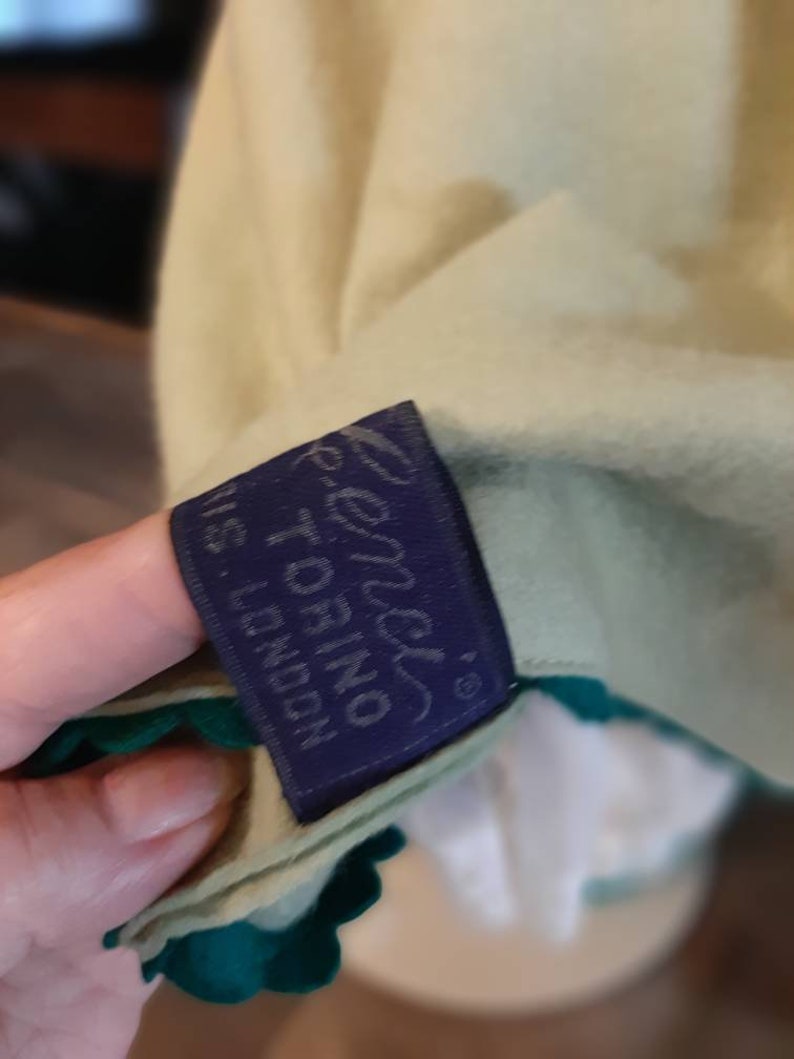 May include: A green and white garment with a blue label that reads "Renzi's Torino, N.S. London".