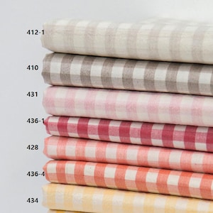 May include: A stack of fabric rolls in various colors, each with a classic gingham check pattern. Colors include beige, gray, pink, red, coral, and yellow. Each roll is labeled with a number. The fabric appears to be cotton or a similar material.