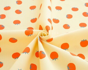 May include: A yellow fabric with a repeating pattern of red tomatoes. The fabric is folded in a spiral shape.
