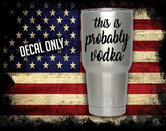 May include: A stainless steel tumbler with a black decal that reads "This is probably vodka" against a backdrop of an American flag.