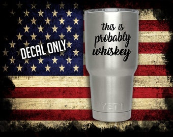 May include: A stainless steel tumbler with a black vinyl decal that reads "this is probably whiskey". The tumbler is on a distressed American flag background.