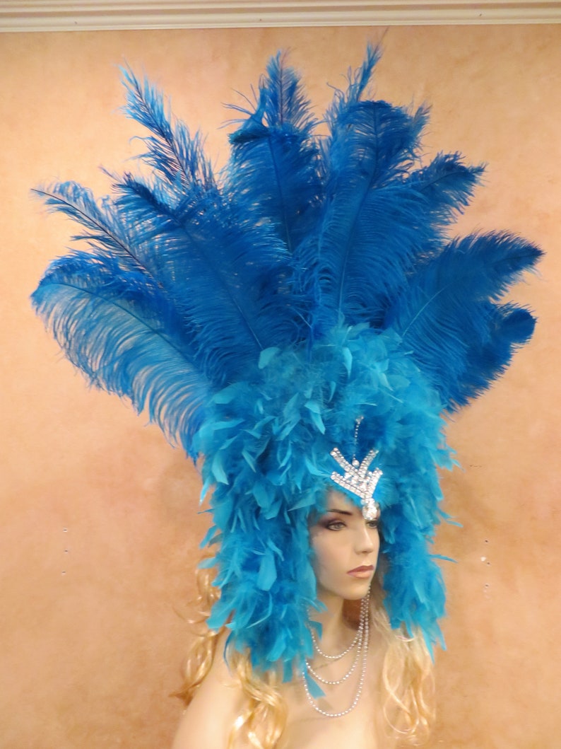 K&ouml;nnte beinhalten: Ein blauer Federkopfschmuck mit einer Strasskrone. Der Kopfschmuck besteht aus langen, flie&szlig;enden Federn und ist perfekt f&uuml;r ein Kost&uuml;m oder eine Party.