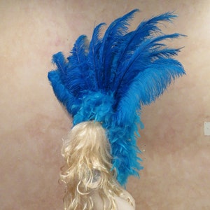 K&ouml;nnte beinhalten: Ein blauer Federkopfschmuck mit einer gro&szlig;en Federhaube oben. Der Kopfschmuck ist aus blauen Federn gefertigt und hat einen blauen Federbesatz.