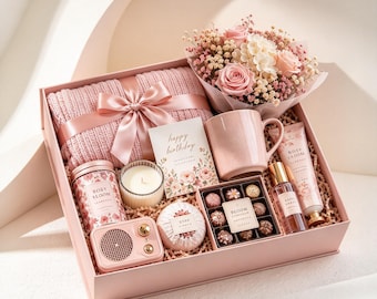May include: A pink gift box containing a knitted blanket with a satin ribbon, a bouquet of pink roses and baby's breath, a ceramic mug, a candle, a small speaker, a bath bomb, chocolates, a perfume bottle, and a tube of hand cream.