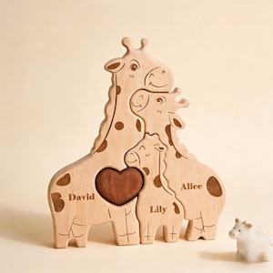 May include: Wooden giraffe family puzzle with a heart-shaped centre. The puzzle is made of light-coloured wood with brown spots and includes the names "David", "Lily", and "Alice". A small white figurine is in the background.