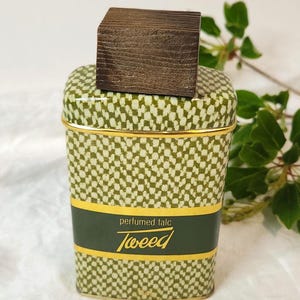 May include: Vintage 'Tweed' perfumed talc container with a wooden lid. The container features a green and white patterned design with gold trim. The label reads "perfumed talc Tweed". The container is rectangular with rounded edges.