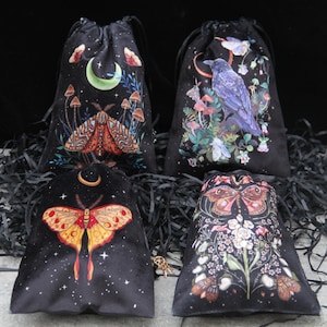 May include: Four black velvet drawstring bags with celestial and nature-themed designs. One bag features a moth and crescent moon, another a raven, and two others showcase moths and floral patterns. Each bag has a black drawstring closure.