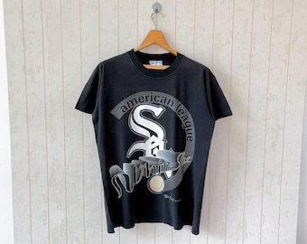 Puede incluir: Camiseta negra con un gráfico blanco del logotipo de los Chicago White Sox, incluyendo el texto "American League" y "White Sox".