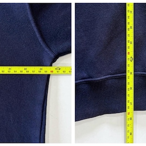 May include: Navy blue sweatshirt with measurements shown. The width is approximately 61 cm, and the length is approximately 76 cm. The sweatshirt has a ribbed hem and cuffs.