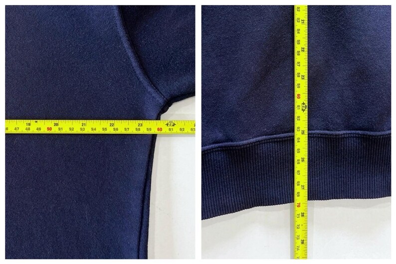 May include: Navy blue sweatshirt with measurements shown. The width is approximately 61 cm, and the length is approximately 76 cm. The sweatshirt has a ribbed hem and cuffs.