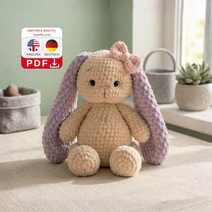 Könnte beinhalten: Ein handgehäkelter Hase in Creme und Lavendel. Der Hase hat lange, schlaffe Lavendelohren, einen cremefarbenen Körper und eine kleine rosa Schleife. Das Bild enthält ein digitales Vorlagenetikett mit dem Text "EDITABLE DIGITAL TEMPLATE" und "PDF".