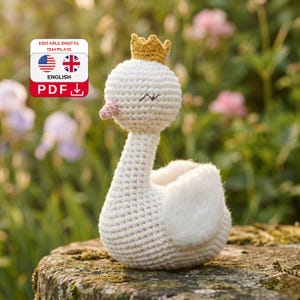 Puede incluir: Un cisne blanco tejido a ganchillo con una corona amarilla y un pico rosa. El cisne tiene los ojos cerrados y alas blancas y esponjosas. La imagen incluye una etiqueta de plantilla digital con el texto "EDITABLE DIGITAL TEMPLATE" y "ENGLISH PDF".