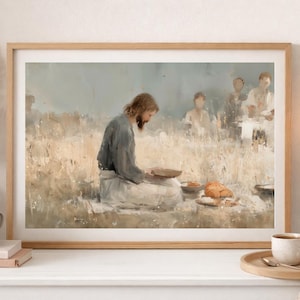 May include: A framed art print depicting a religious scene with a central figure in a blue robe, seated and holding a plate. The artwork has a muted color palette with beige and light brown tones, and is displayed on a white surface.