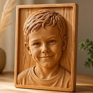 May include: A wooden relief carving of a smiling child's face, set within a rectangular frame. The carving is detailed, showing the child's hair, facial features, and a t-shirt. The wood has a natural, light brown color.