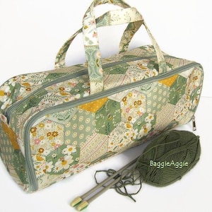 May include: A rectangular fabric bag featuring a patchwork of hexagonal patterns in shades of sage green, mustard yellow, and cream with floral and bee motifs. The bag has two top handles, a zippered closure, and is accompanied by a ball of olive green yarn.