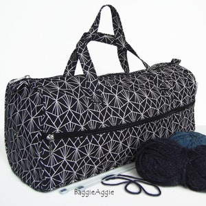 May include: Black and white geometric print travel bag with two zipped compartments, two balls of yarn, and knitting needles. The bag has two top handles.