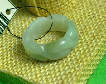 May include: A light green jade ring with a textured, wavy design. The ring is displayed on a woven fabric surface.