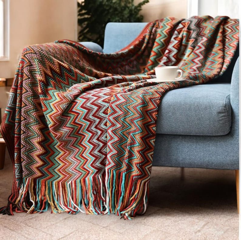 May include: A colourful throw blanket with a chevron pattern and fringe. The blanket is draped over a blue armchair.
