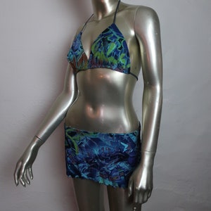 May include: A blue and green patterned bikini top and matching skirt. The bikini top has a triangle shape and thin straps. The skirt is a mini skirt with a ruffled hem.