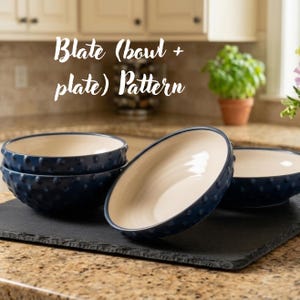 Puede incluir: Un juego de cuencos y platos de cerámica azul oscuro con una textura de puntos en relieve en el exterior y un interior liso de color crema. El texto "Blate (bowl + plate) Pattern" es visible en letra blanca sobre la vajilla azul oscuro.