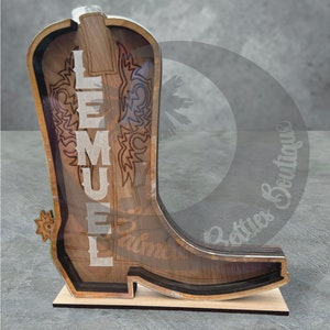 May include: Wooden cowboy boot cutout with a clear acrylic insert. The boot has a decorative design and the name "LEMUEL" is engraved on the side.