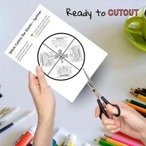 May include: A white paper spinner titled "Jesus Calms the Storm" is being cut with scissors. The spinner has a circular design divided into four sections with illustrations and numbers. The words "Ready to CUTOUT" are written at the top.