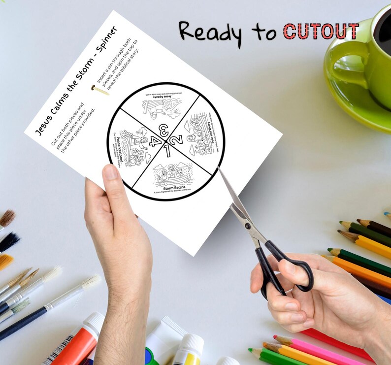 May include: A white paper spinner titled "Jesus Calms the Storm" is being cut with scissors. The spinner has a circular design divided into four sections with illustrations and numbers. The words "Ready to CUTOUT" are written at the top.