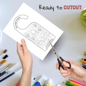May include: A white paper door hanger featuring a black line drawing of angels, a throne, and people. The text "God reigns in glory" and "John sees God's throne surrounded by worshipers" are included. The words "Ready to CUTOUT" are at the top.
