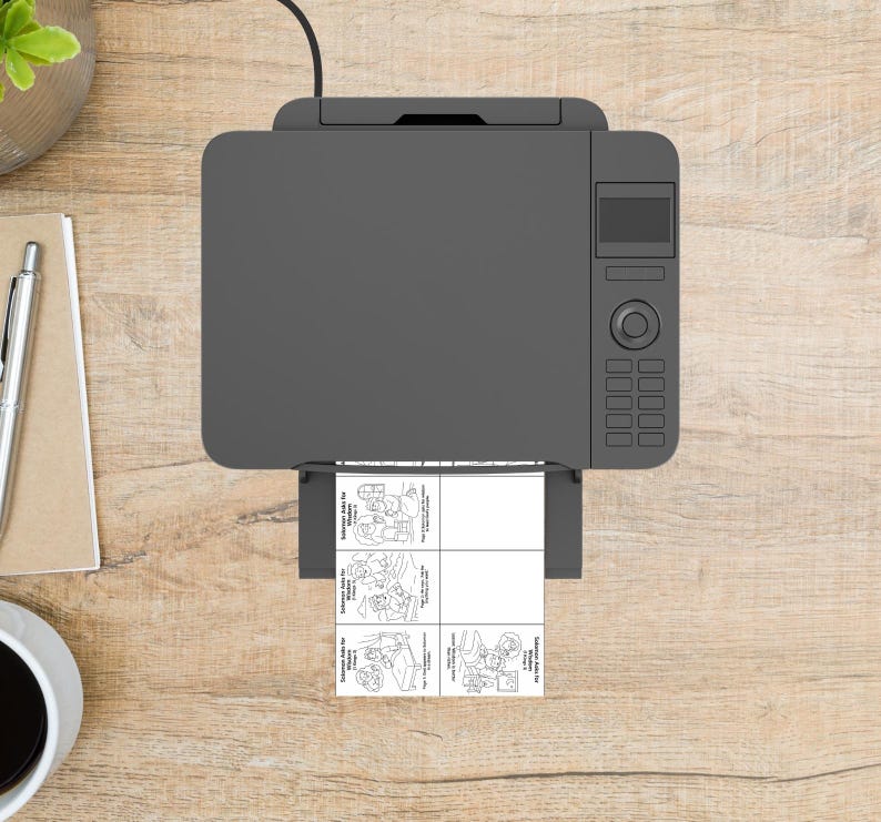 May include: A grey printer on a wooden desk, printing a sheet with four black and white cartoon illustrations. A pen, notepad, and coffee cup are also visible. The image is taken from above.