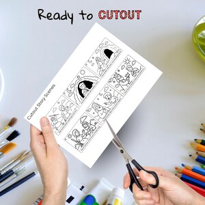 May include: A person's hands are holding a white sheet of paper with black and white illustrations and text, and cutting it with scissors. The text on the paper says "Cutout Story Scenes" and "Ready to CUTOUT".