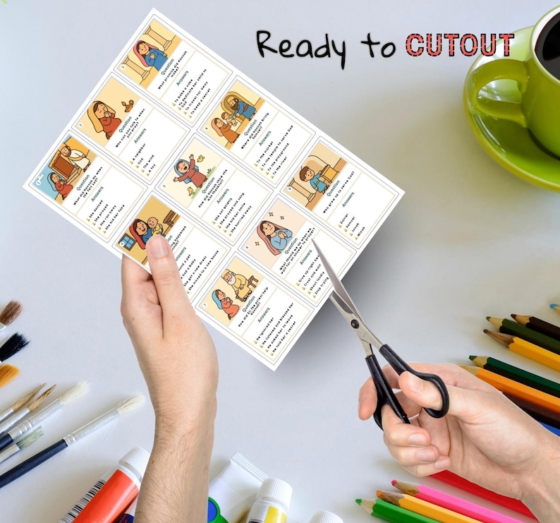 Puede incluir: Una hoja de papel con tarjetas ilustradas con preguntas y respuestas, sostenida por manos. El texto "Ready to CUTOUT" est&aacute; escrito en la parte superior. Las tijeras est&aacute;n cortando el papel. Una taza verde y l&aacute;pices de colores est&aacute;n en el fondo.