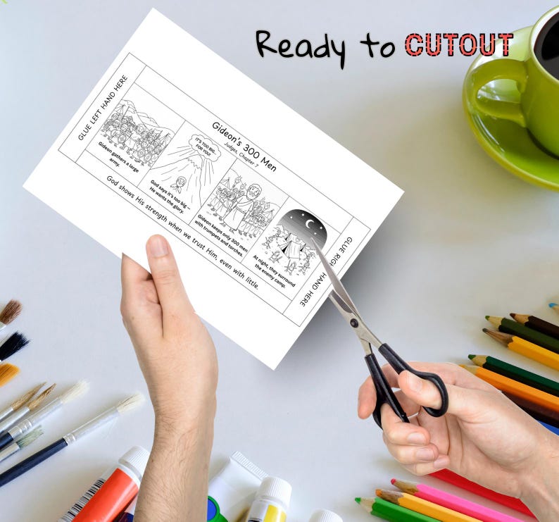 May include: A white paper with illustrations and text about Gideon's 300 Men is being cut with scissors. The text includes "Ready to CUTOUT" and "Gideon's 300 Men". A green mug and art supplies are in the background.