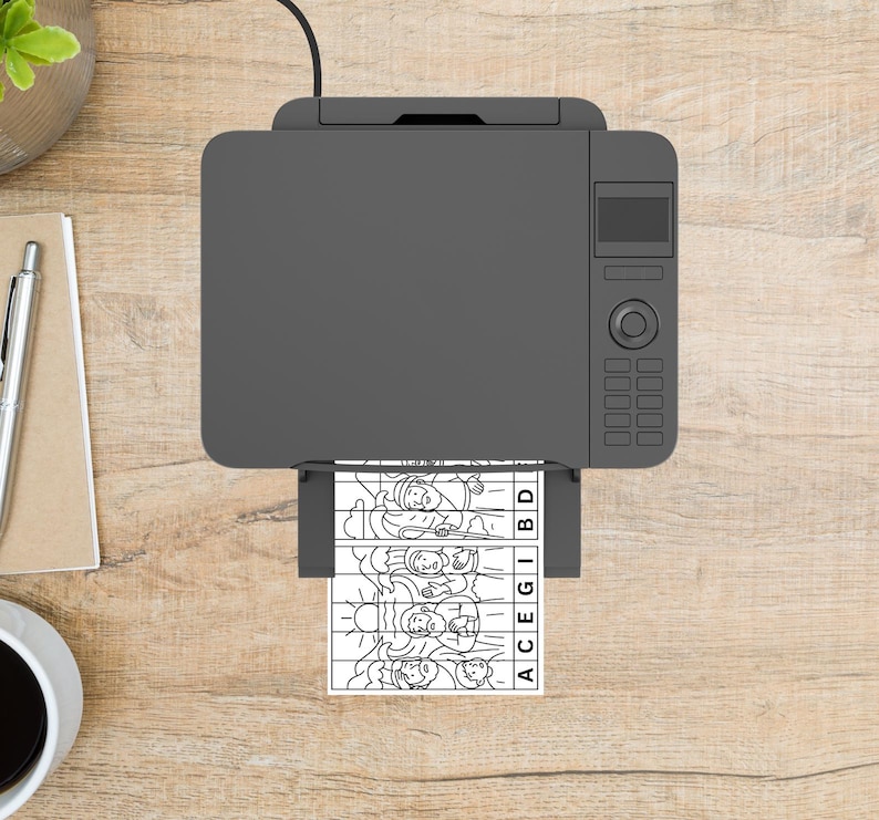 May include: A gray printer is printing a black and white image of a puzzle on a wooden desk. The puzzle shows a line drawing of people and the letters ACEGIBD. A pen, notepad, and coffee cup are also on the desk.