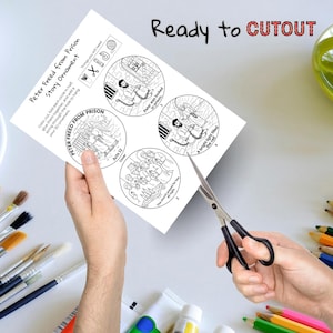 May include: A black and white paper craft with the text "Peter Freed from Prison Story Ornament" and illustrations of a Bible story. The paper is being cut with scissors. The text "Ready to CUTOUT" is at the top.