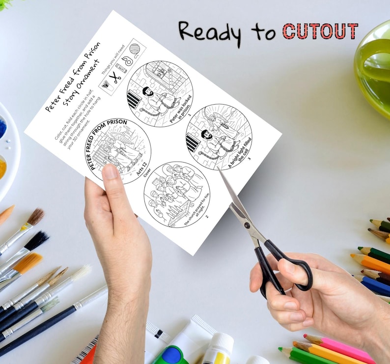May include: A black and white paper craft with the text "Peter Freed from Prison Story Ornament" and illustrations of a Bible story. The paper is being cut with scissors. The text "Ready to CUTOUT" is at the top.