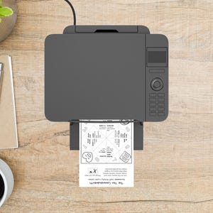 K&ouml;nnte beinhalten: Draufsicht auf einen grauen Drucker, der ein wei&szlig;es Blatt Papier bedruckt. Das Papier hat ein geometrisches Design mit dem Text "The Ten Commandments". Ein Stift, ein Notizblock und eine Kaffeetasse sind sichtbar.