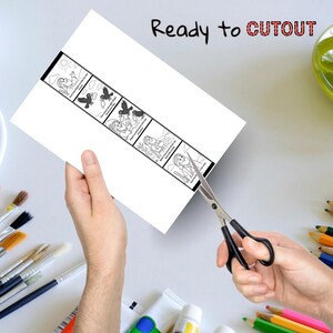 May include: A white paper strip with a black border featuring a sequential illustration of a woman and birds. The text "Ready to CUTOUT" is written at the top. Scissors are cutting the paper. Paintbrushes, paint tubes, and colored pencils are in the background.