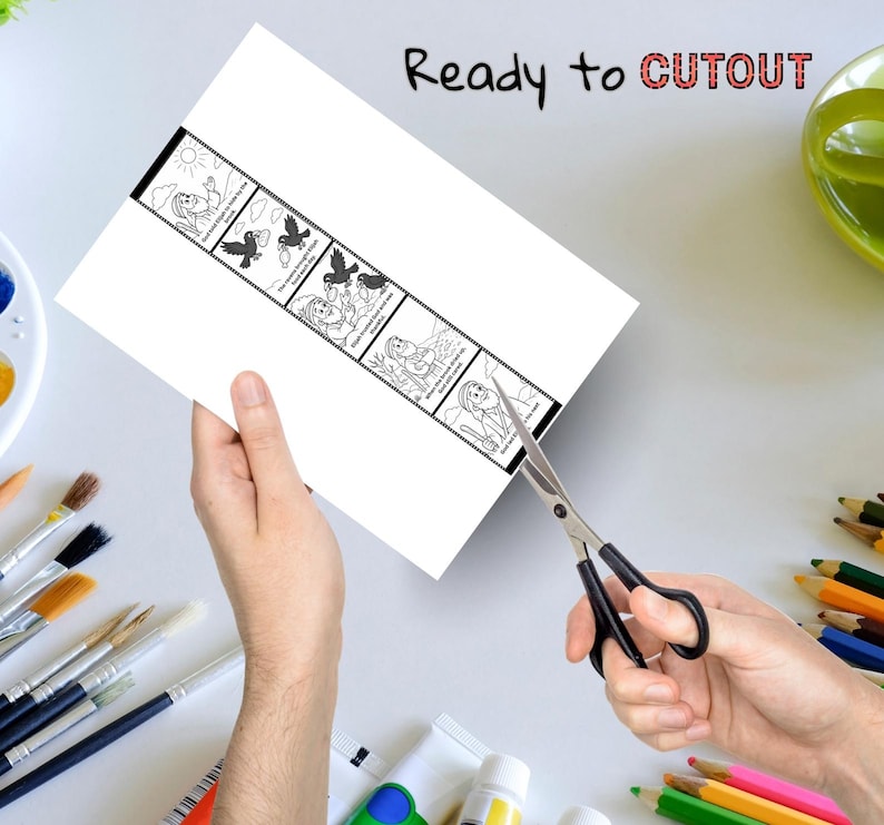 May include: A white paper strip with a black border featuring a sequential illustration of a woman and birds. The text "Ready to CUTOUT" is written at the top. Scissors are cutting the paper. Paintbrushes, paint tubes, and colored pencils are in the background.