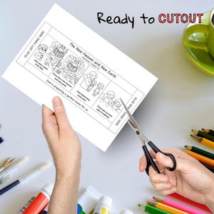 May include: A black and white illustrated paper with the text "The New Heaven and New Earth" is being cut with scissors. The paper has illustrations and text, including "Ready to CUTOUT". A green mug and colored pencils are in the background.